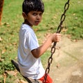 Smart Asian boy riding on swing in society park, happy boy play outdoors in summer, baby boy playing swing in the garden Royalty Free Stock Photo