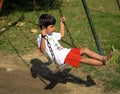 Smart Asian boy riding on swing in society park, happy boy play outdoors in summer, baby boy playing swing in the garden Royalty Free Stock Photo