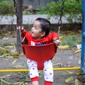 Smart Asian boy riding on swing in society park, happy boy play outdoors in summer, baby boy playing swing in the garden Royalty Free Stock Photo