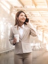 Smart asian business woman in a suit with mobile phone and holding a paper cup of coffee, outside corporate office. Royalty Free Stock Photo