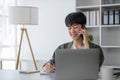 Smart Asian businessman in casual clothing using smartphone and laptop computer working at home office. Male manager Royalty Free Stock Photo