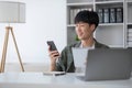 Smart Asian businessman in casual clothing using smartphone and laptop computer working at home office. Male manager Royalty Free Stock Photo