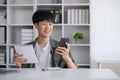 Smart Asian businessman in casual clothing using smartphone and laptop computer working at home office. Male manager Royalty Free Stock Photo