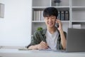 Smart Asian businessman in casual clothing using smartphone and laptop computer working at home office. Male manager Royalty Free Stock Photo