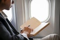 Smart Asian businessman is on the flight, checking his schedule on his notebook or diary. cropped Royalty Free Stock Photo