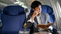 Smart Asian businessman on the plane, planning his business while looking out the window Royalty Free Stock Photo