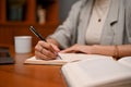 Smart Asian businesswoman writing something on her notebook during working in her office