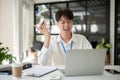 A smart Asian male banker is having an online meeting with his team while sitting at his desk Royalty Free Stock Photo