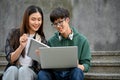 Smart Asian male college student is using laptop, talking and working on project with his girl friend Royalty Free Stock Photo