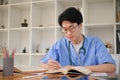 Smart Asian male medical student focuses on reading a book in the medical school library Royalty Free Stock Photo