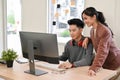 Smart Asian male programmer or developer working with his female manager on computer Royalty Free Stock Photo