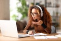 Focused afro american female having video call while working remotely or studying online on laptop from home Royalty Free Stock Photo