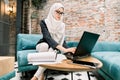 Smart attractive muslim businesswoman using laptop for working online, writing e-mail to her business partners. Arabian Royalty Free Stock Photo