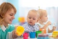 Smart babies in day care. Group of kids playing toys with kindergarten teacher. Children lesson in creche