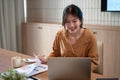 A smart Asian businesswoman is examining business financial reports, using her laptop in office Royalty Free Stock Photo