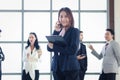 Smart and beautiful young businesswoman with black long hair in suit talking on mobile phone at the window office workplace with Royalty Free Stock Photo