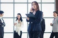 Smart and beautiful young businesswoman with black long hair in suit talking on mobile phone at the window office workplace with Royalty Free Stock Photo