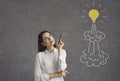 Woman with pen looking at flying light bulb rocket and thinking of her own business startup idea Royalty Free Stock Photo