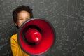 Smart black child with megaphone loudspeaker on chalkboard background with science formulas