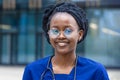 Smart black girl medical student in glasses, happy young african american woman doctor, nurse in blue uniform, stethoscope Royalty Free Stock Photo