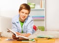 Smart boy with book and textbook lay on the floor