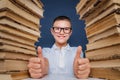 Smart boy in glasses sitting between two piles of books and look Royalty Free Stock Photo