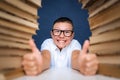 Smart boy in glasses sitting between two piles of books and look Royalty Free Stock Photo