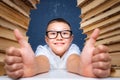 Smart boy in glasses sitting between two piles of books and look up thoughtfully Royalty Free Stock Photo