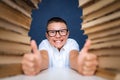 Smart boy in glasses sitting between two piles of books and look up thoughtfully Royalty Free Stock Photo