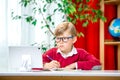 Smart boy in glasses using tablet computer. Child writing homework or preparing for the exam. Teen using laptop to study