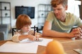 Little boy drawing a dollar sign , his ftaher watching