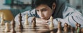 Smart boy playing chess and staring at the chessboard Royalty Free Stock Photo