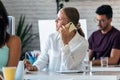 Smart businesswoman talking on mobile phone while working with her computer in the office Royalty Free Stock Photo