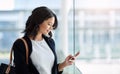 Smart businesswomen make smart connections. an attractive young businesswoman using a smartphone while standing in a