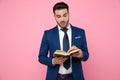 Smart casual man reading book on pink background Royalty Free Stock Photo