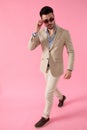 Smart casual man walking and fixing his sunglasses Royalty Free Stock Photo