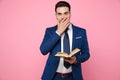 Smart casual man holding a book on pink background Royalty Free Stock Photo