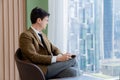 Smart businessman holding coffee cup while looking skyscraper view. Ornamented. Royalty Free Stock Photo