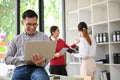 A smart adult Asian businessman is sitting on a desk and working on his laptop in the office Royalty Free Stock Photo