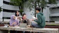 A smart Asian male college student is helping his friends with math in a campus park Royalty Free Stock Photo