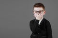 Smart child boy adjusts his glasses with finger on the grey background, close-up. Studio juvenile portrait in casual clothes. copy Royalty Free Stock Photo