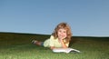 Smart child boy reading book in park outdoor. Clever kids. Kid in t-shirt having fun reading book in park. Royalty Free Stock Photo