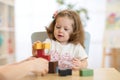 Little child girl plays in kindergarten in Montessori preschool class.