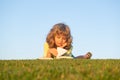 Smart child reading book, laying on grass in field on sky and grass field. Portrait of clever kids.