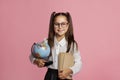 Smart child ready to learn. Smiling schoolgirl in glasses with globe and books Royalty Free Stock Photo