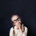 Smart child thinking. Little girl in glasses on chalk board