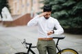 Smart and confident indian businessman looking at his watch while late to meet by bicycle, copy space Royalty Free Stock Photo