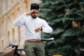 Smart and confident indian businessman looking at his watch while late to meet by bicycle, copy space Royalty Free Stock Photo