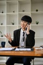 A smart Asian businessman is on the phone with his client, dealing business over the phone Royalty Free Stock Photo