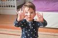 Smart cute child counts fingers. A beautiful kid shows his hand, a small palm. Caucasian boy on a bedroom background